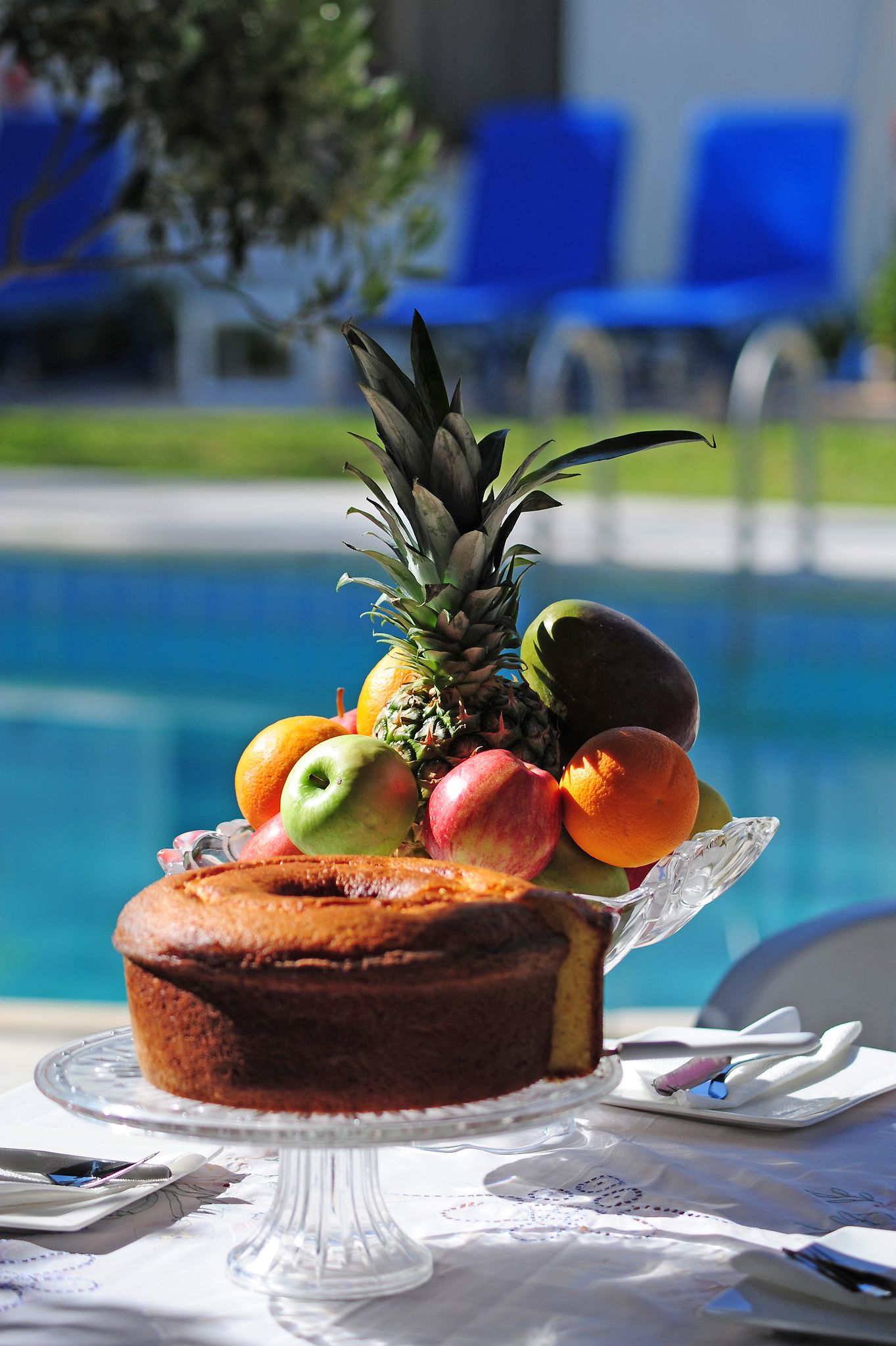 Una bandeja con fruta y pastel junto a una piscina.