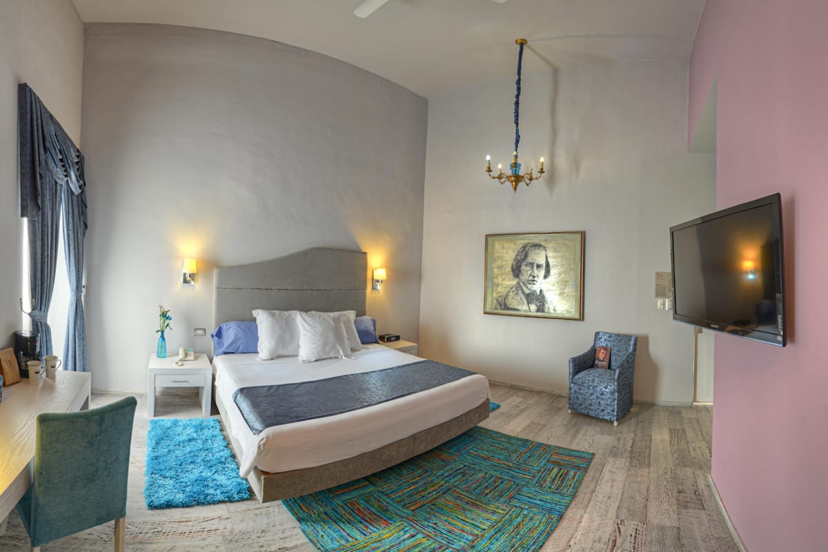 Un dormitorio moderno con una cama grande, un televisor, una silla y un cuadro en la pared.