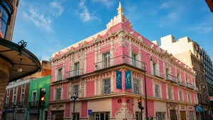 A pink building with balconies and a clock tower, featuring a storefront with a bicycle sign. - Hotel Andante (Puebla)