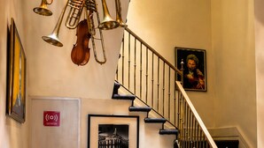 A staircase with a brass railing, a red velvet chair, and two bicycles. - Hotel Andante (Puebla)