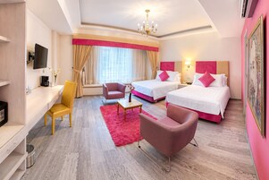 Een hotelkamer met twee bedden, een bureau, een stoel, een televisie en een raam met gordijnen.