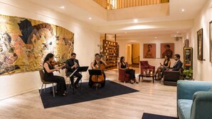 A spacious lobby with a high ceiling, a mezzanine level, and a large abstract painting on the wall. - Hotel Andante (Puebla)