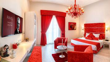 A hotel room with a bed, a desk, a chair, a red carpet, and a chandelier.