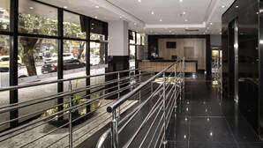 Un vestíbul d'hotel modern amb façana de vidre, barana metàl·lica i sòl net i polit.