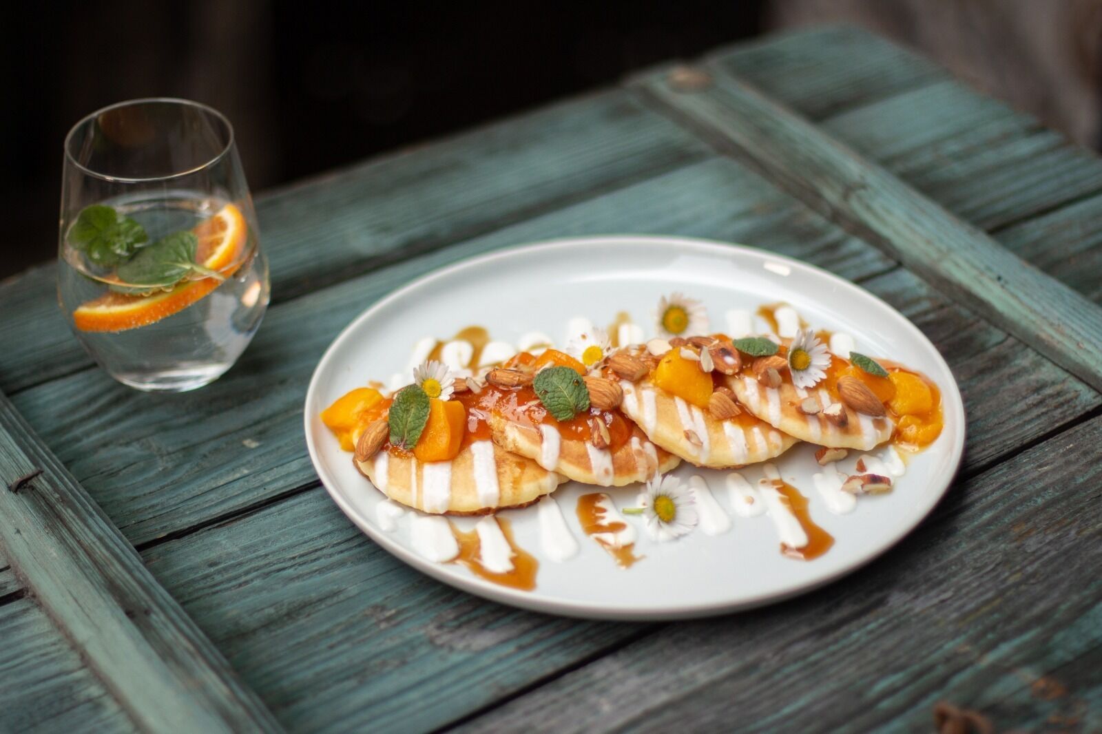 Une assiette de crêpes garnies de fruits et de noix, posée sur une table en bois.