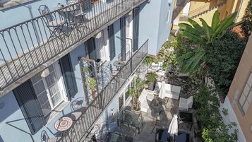Un patio con asientos al aire libre, una escalera y una planta grande.