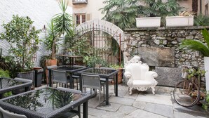 An outdoor patio with wicker furniture, a white armchair, and potted plants. - Caffè dell'Arte Boutique Rooms Locarno (Locarno)