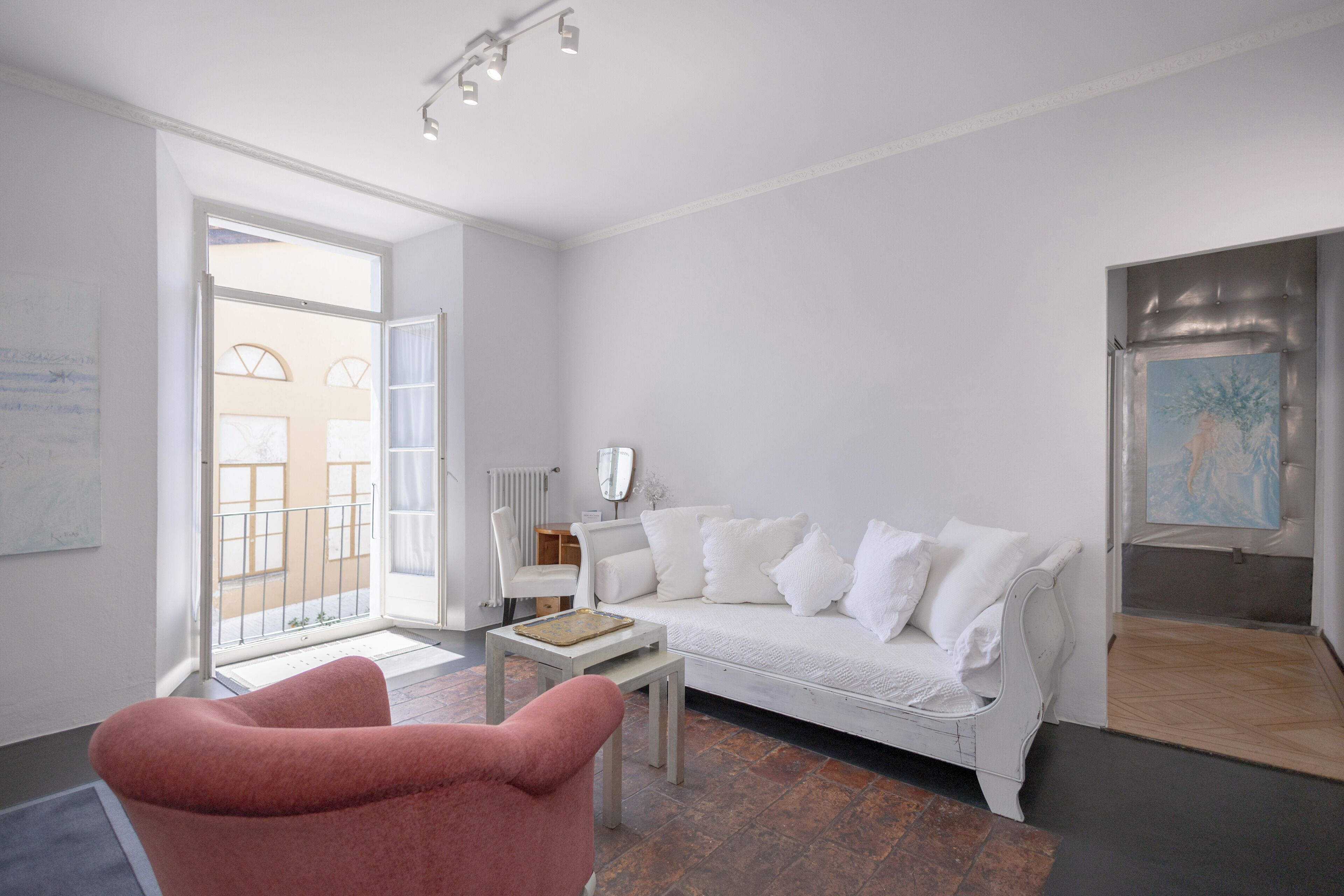 A modern living room with a white sofa, a pink armchair, and a small table.