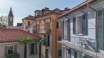 Una hilera de edificios europeos tradicionales con balcones, una aguja de iglesia y cielo despejado.