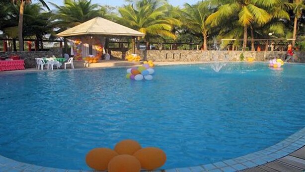 A swimming pool with palm trees and a shaded area. - Pattaya Country Club (Bang Lamung)