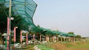 A covered outdoor seating area with tables and chairs, a pathway, and a green landscape. - Pattaya Country Club (Bang Lamung)