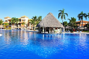 A resort pool with a thatched-roof structure, palm trees, and multi-story buildings. - Bahia Principe Explore Turquesa - Hyatt Inclusive Collection - All Inclusive (Punta Cana)