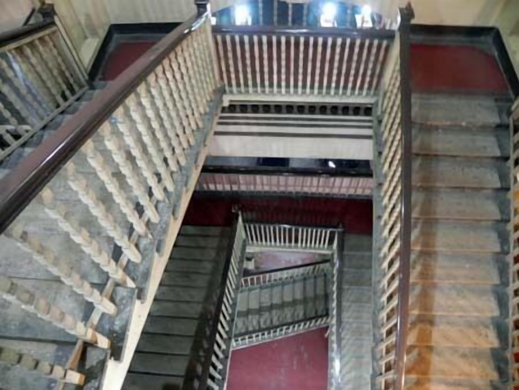 Un escalier à plusieurs niveaux, doté de rampes en bois et de garde-corps en métal.