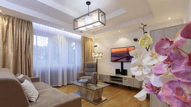 A modern living room with a glass coffee table, a sofa, a chair, and a TV on a stand. - The Queen Luxury Apartments - Villa Giada (Hesperange)