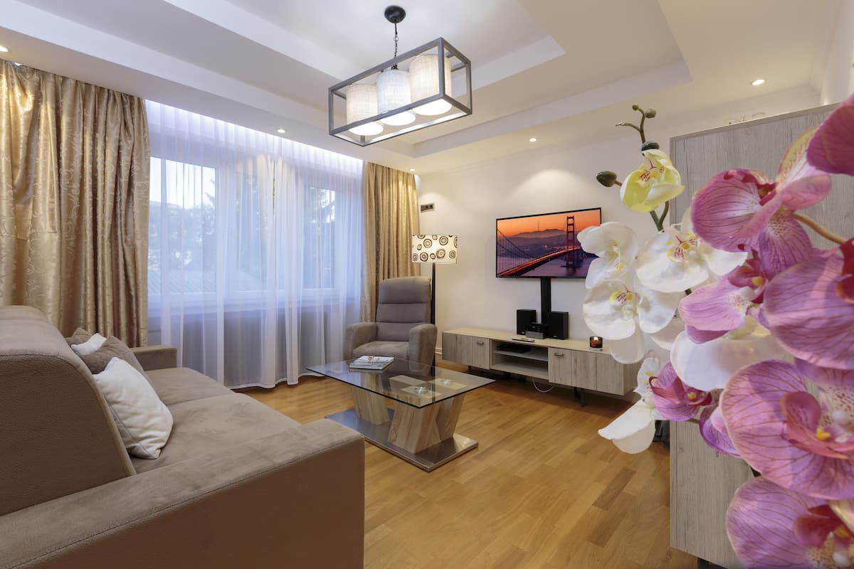 A modern living room with a glass coffee table, a sofa, a chair, and a TV on a stand.