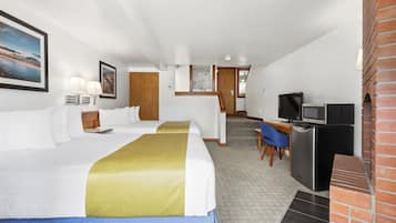 A hotel room with two beds, a desk with a computer, a television, and a brick fireplace.