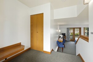A hotel room with a wooden bench, a desk with a chair, and a balcony with a view.
