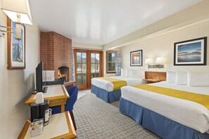 A hotel room with two beds, a desk with a computer, a coffee maker, and a fireplace. - Canadian Princess Lodge & Marina (Ucluelet)