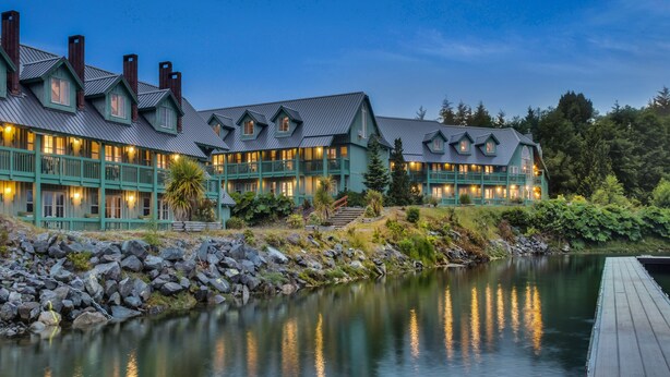 A large, multi-story hotel with a waterfront view, featuring a dock and a rocky shoreline. - Canadian Princess Lodge & Marina (Ucluelet)