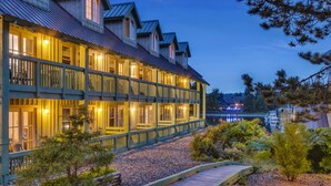 A multi-story hotel with a wooden facade, a covered outdoor area, and a view of a lake. - Canadian Princess Lodge & Marina (Ucluelet)