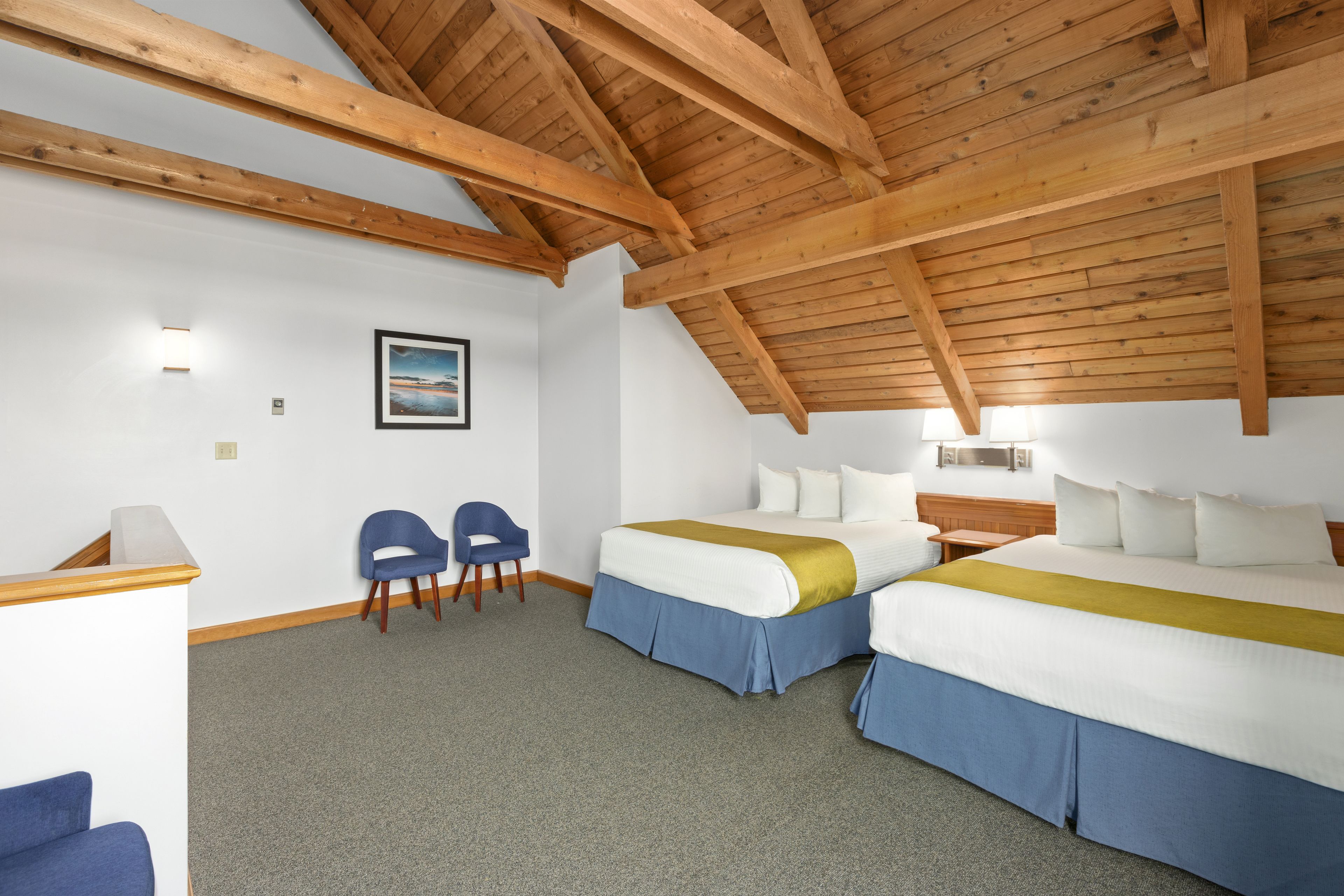 A hotel room with two beds, a desk, and a chair.