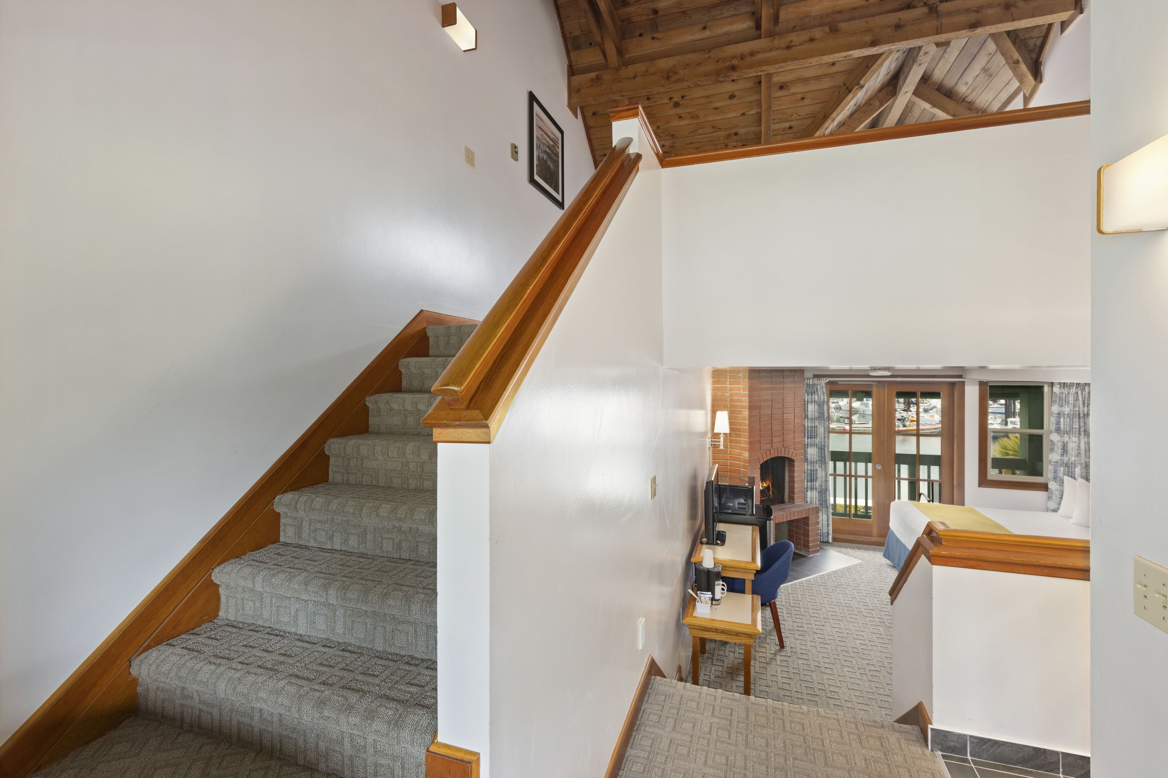 A staircase leading to a room with a fireplace, a desk, and a view of the outdoors.