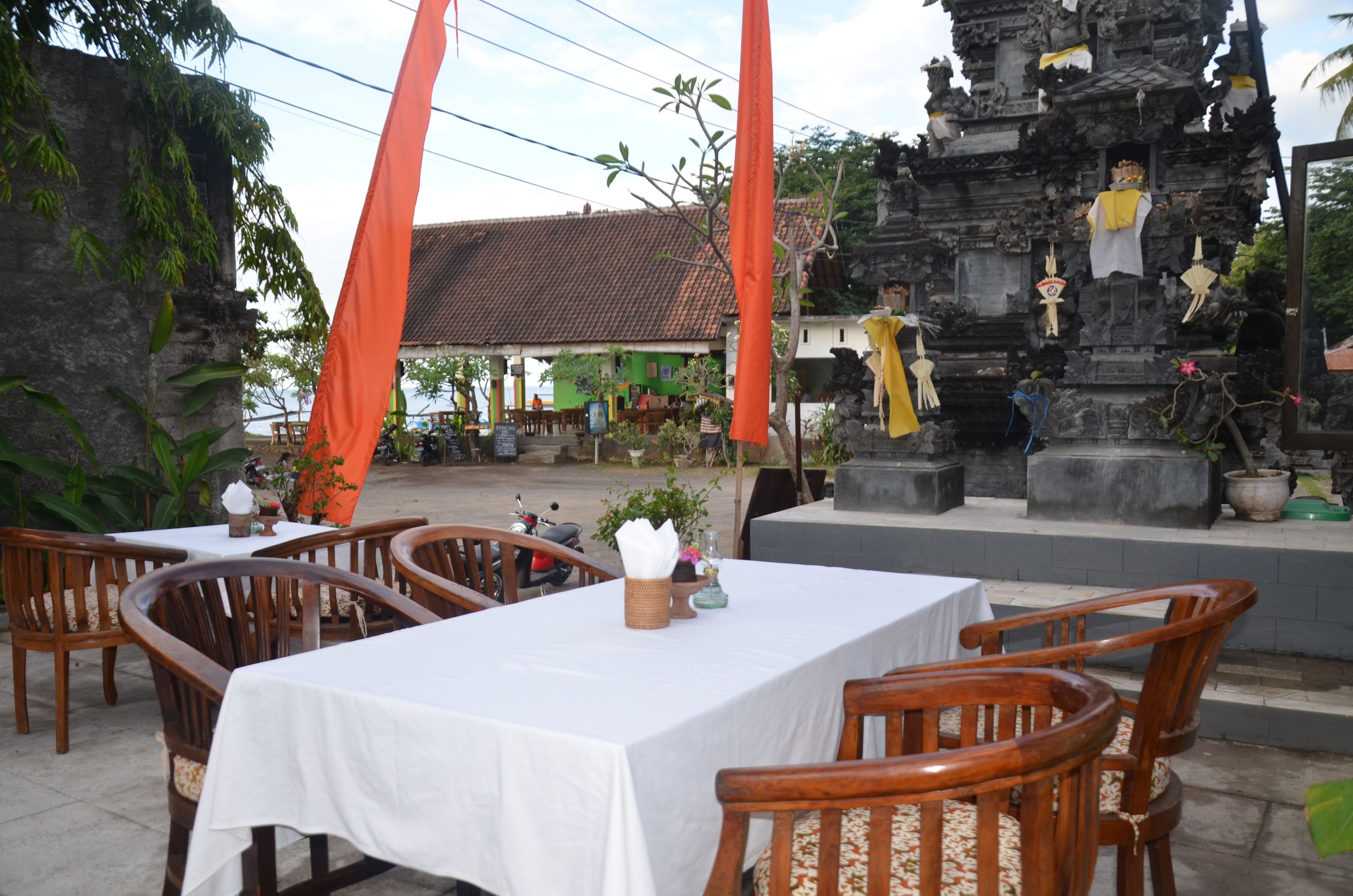 A restaurant with outdoor seating, a temple-like structure in the background, and a green building.