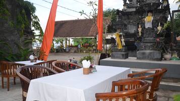 A restaurant with outdoor seating, a temple-like structure in the background, and a green building.
