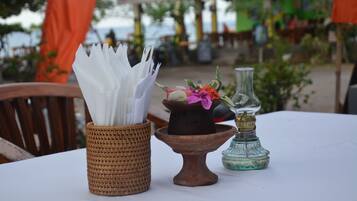 A table with a woven basket holding napkins, a clay pot with flowers, and a glass bottle.