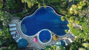 Una piscina al aire libre, sombrillas, sillones reclinables de piscina