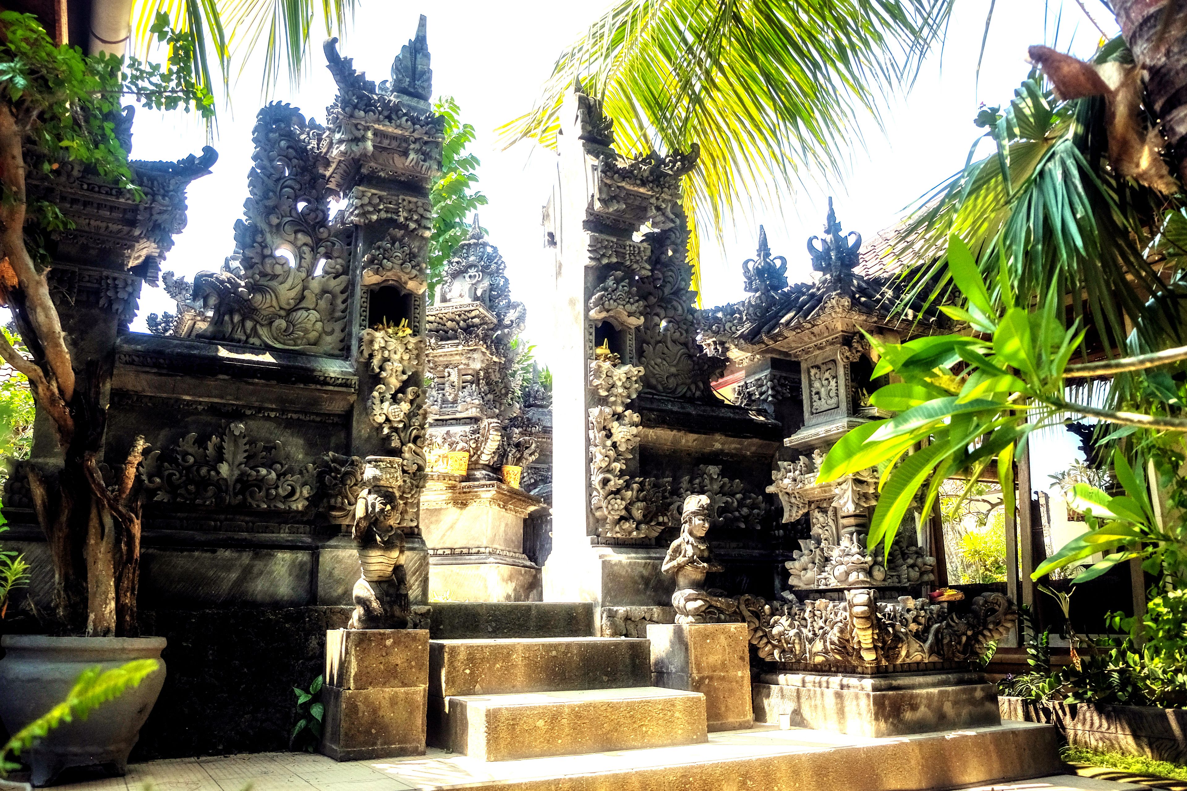 Un templo balinés tradicional con elaboradas esculturas, una estatua central y una escalera que conduce a la entrada.