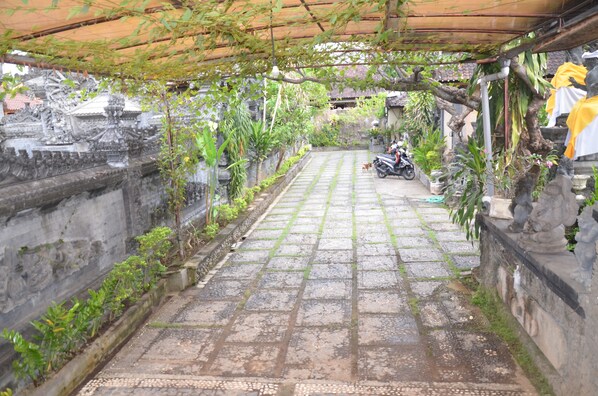A stone pathway leading to a temple with statues and plants. - Hotel Suma (Buleleng)