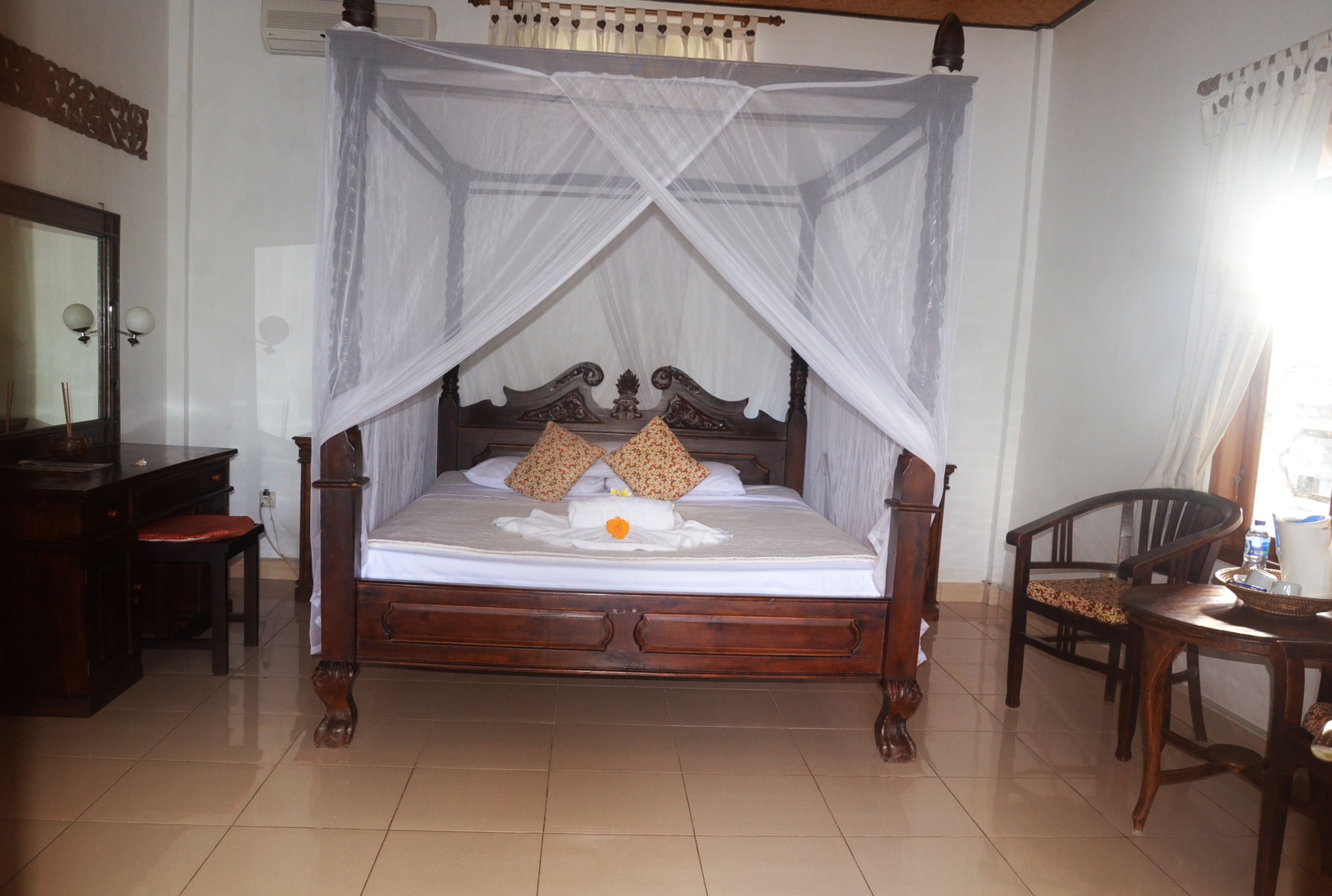 A four-poster canopy bed with a wooden headboard, two pillows, and a white bedspread.