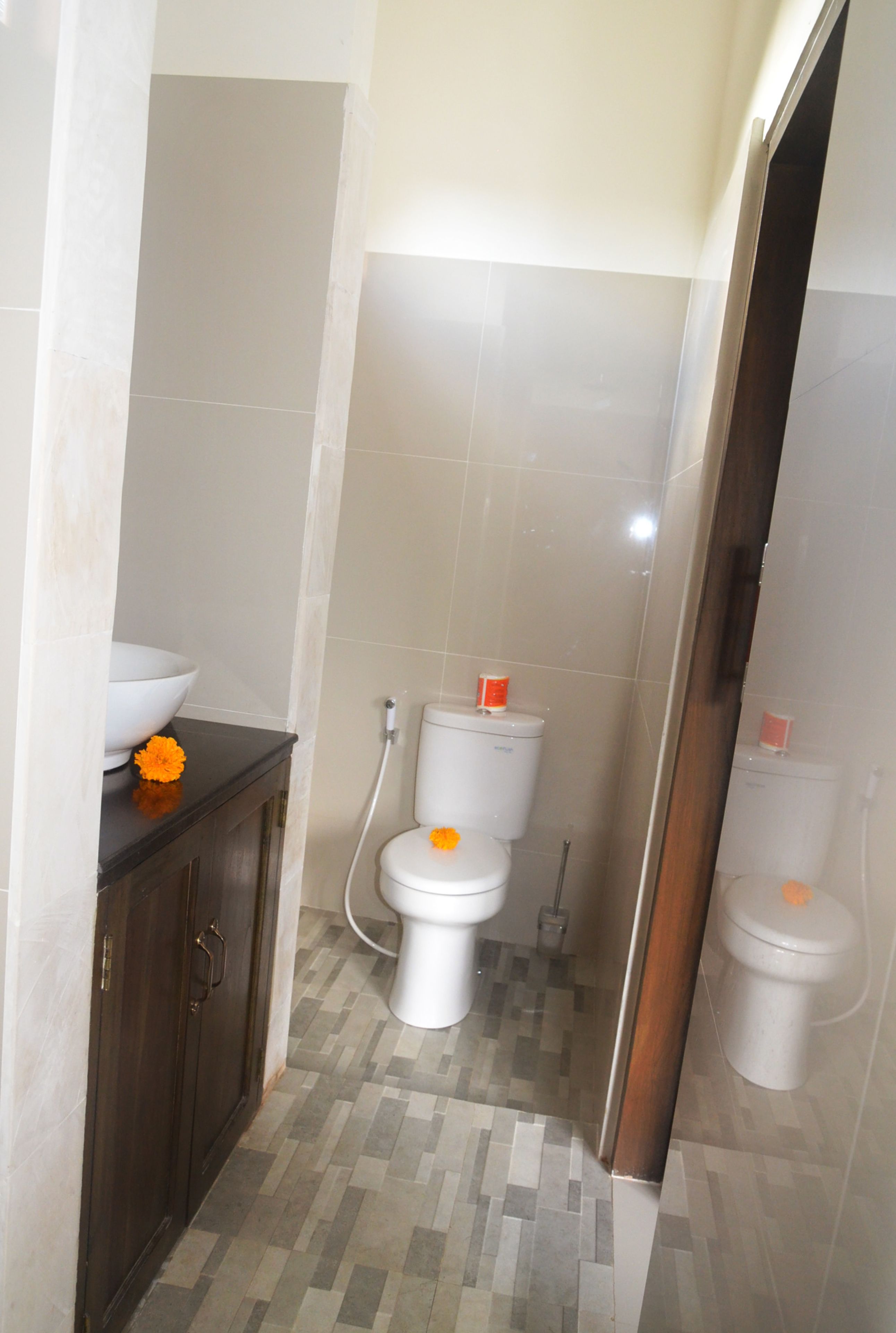 Een badkamer met twee toiletten, een wastafel en een kast.