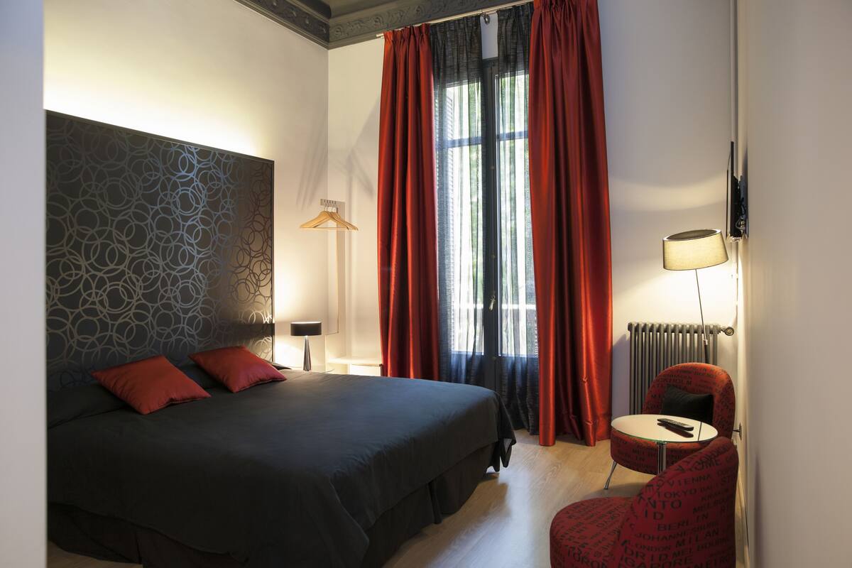 Et moderne hotelværelse med en stor seng, et lille rundt bord og en rød stol.