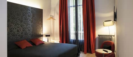 Une chambre d’hôtel moderne avec un grand lit, une petite table ronde et une chaise rouge.