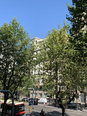 Un edificio de varios pisos con estilo arquitectónico clásico, rodeado de árboles y un cielo azul despejado.