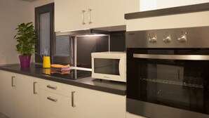Una cocina moderna con armarios blancos, un microondas, un horno y una planta en la encimera.