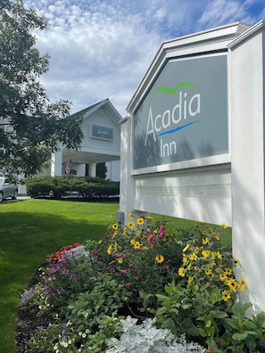 A sign for Acadia Inn with a clear view of the building and a well-maintained garden in front. - Acadia Inn (Bar Harbor)