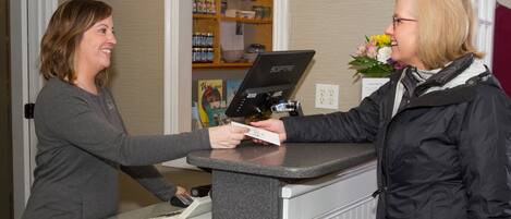A reception desk with a counter, a computer, and a cash register.