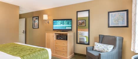 A hotel room with a bed, a chair, a television, a dresser, and a map on the wall.