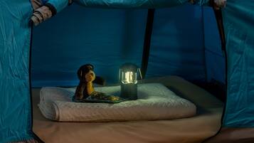A tent with a sleeping area, a lantern, and a stuffed toy.