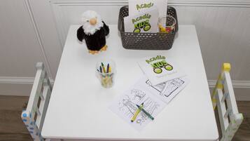 A small table with a plush toy, a basket with cards, a cup with markers, and a couple of coloring sheets.