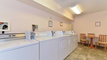 A laundry area with multiple washing machines, a clock, and a small table with chairs.