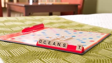 Une partie de Scrabble se déroule sur un lit recouvert d’une couvre-lit à motifs verts.