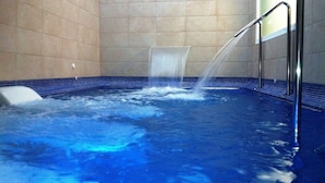 Ein Whirlpool mit Wasserstrahlen, umgeben von gefliesten Wänden.