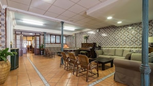 Eine geräumige Lobby mit Klavier, Sofas und Essbereich.