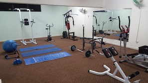 A gym with exercise equipment, mats, and a mirrored wall. - Mandalena Hotel Apts (Paralimni)
