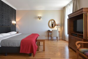 A hotel room with a bed, a desk, a chair, a television, and a mirror.