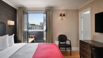 A hotel room with a bed, a desk, a chair, a dresser, and a TV.